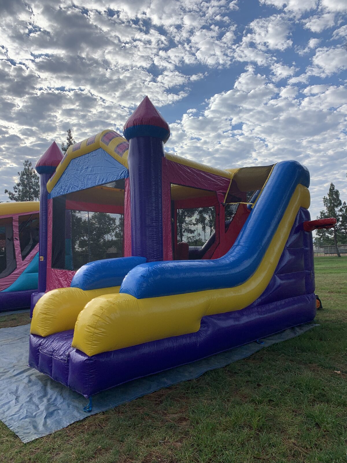 6n1 dream castle combo bounce house rental in San Diego, close-up of the blue and yellow slide exit under a cloudy sky