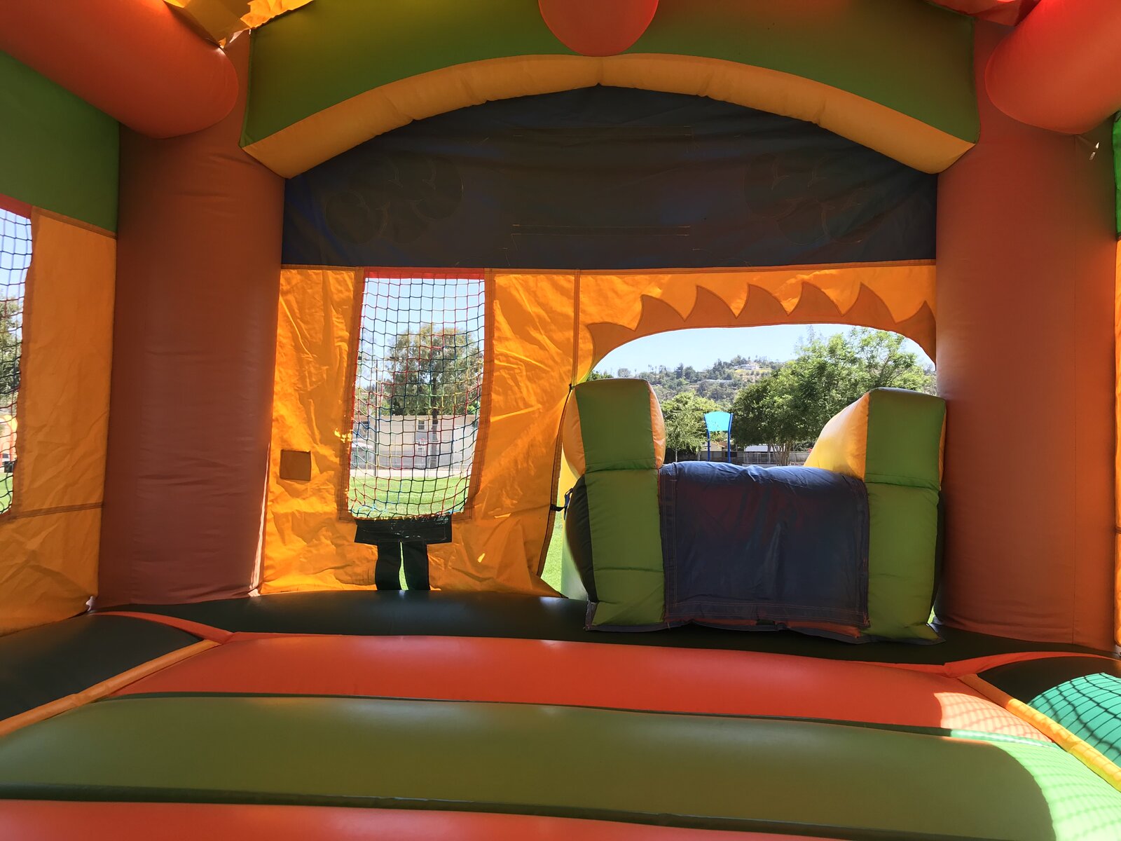2n1 palm tree combo bounce house rental in San Diego, wide interior view of the jump area with the slide tunnel and park view beyond