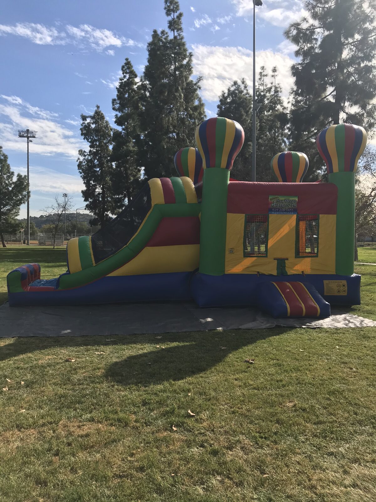 4n1 balloon castle combo bounce house rental in San Diego, full side view showing the slide lane, entry step, and striped balloon towers