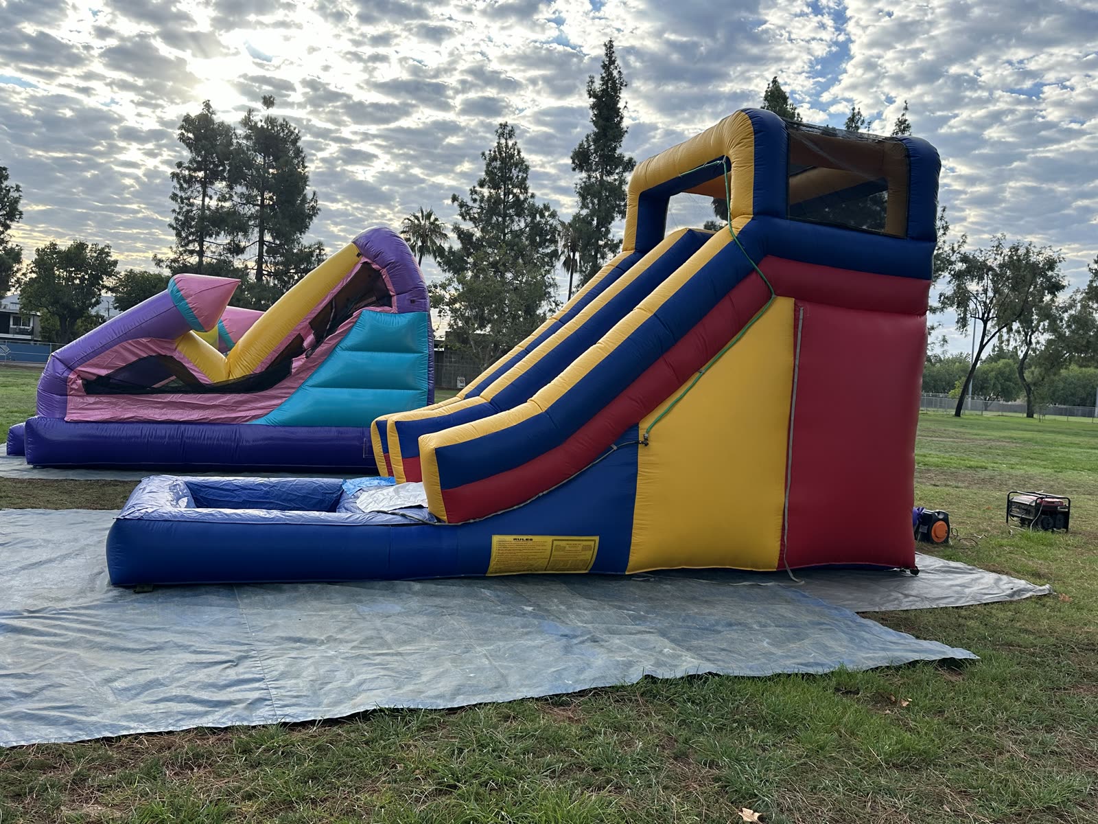 Water slide rental in San Diego, 15ft multi color water slide setup at a park with the blower running beside it
