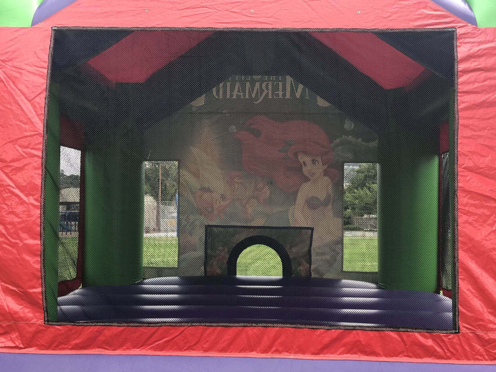13x13 Ariel bounce house rental in San Diego — view through the mesh safety netting into the jumping area and basketball hoop