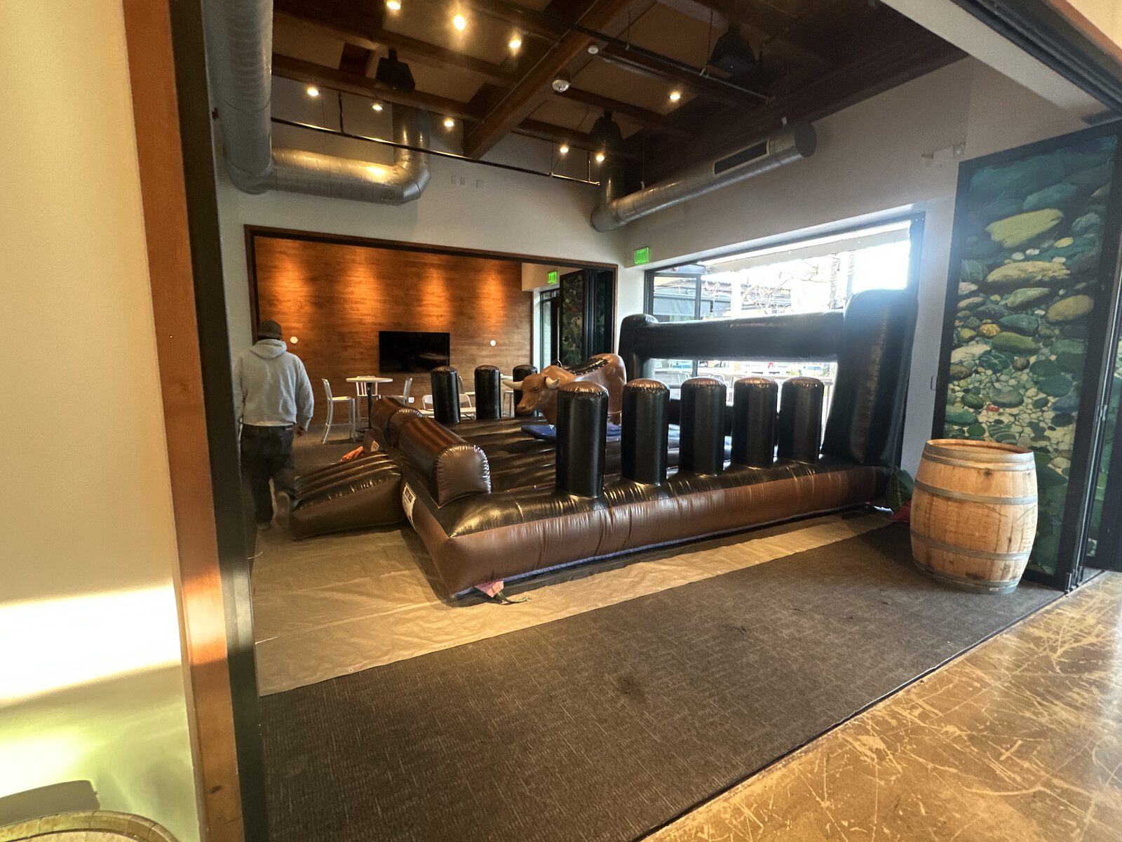 Mechanical bull rental in San Diego, 13x13 setup seen through open venue doors next to a wine barrel