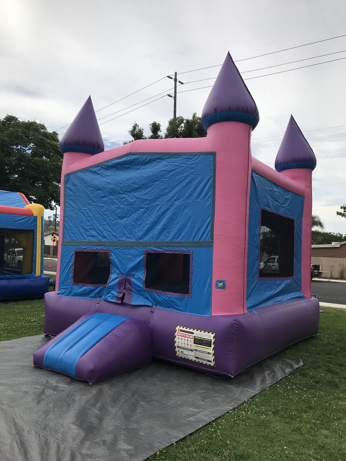 13x13 Pink Castle Banner bounce house rental in San Diego — rear-angled view set up on a tarp with safety rules panel visible