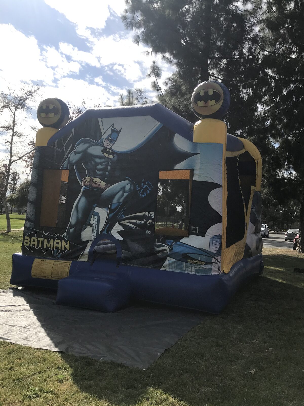 4n1 Batman combo bounce house rental in San Diego, three-quarter view of the front art panel and yellow side wall with mesh window