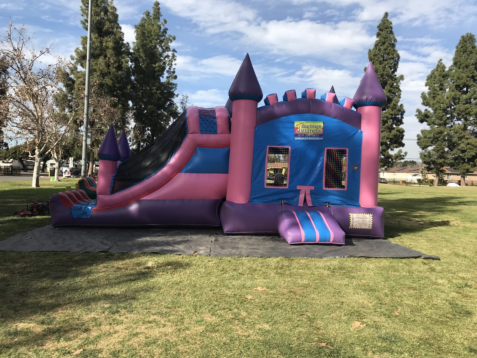 4n1 pink castle combo bounce house rental in San Diego, full side view with the blue banner panel, slide, and striped entry step