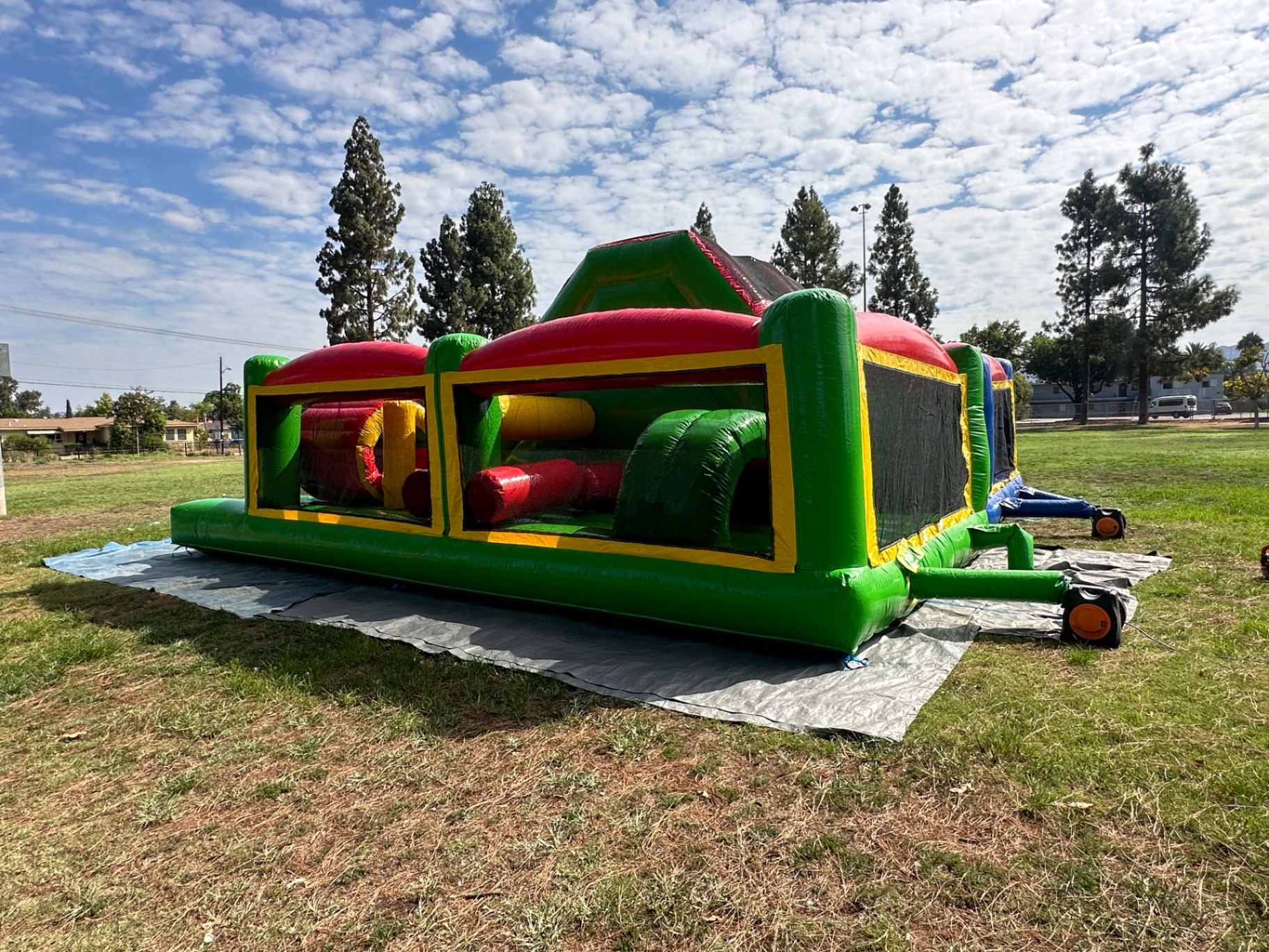 Dual lane challenge course obstacle rental in San Diego, green lane end view showing the pop-up obstacles through the mesh windows