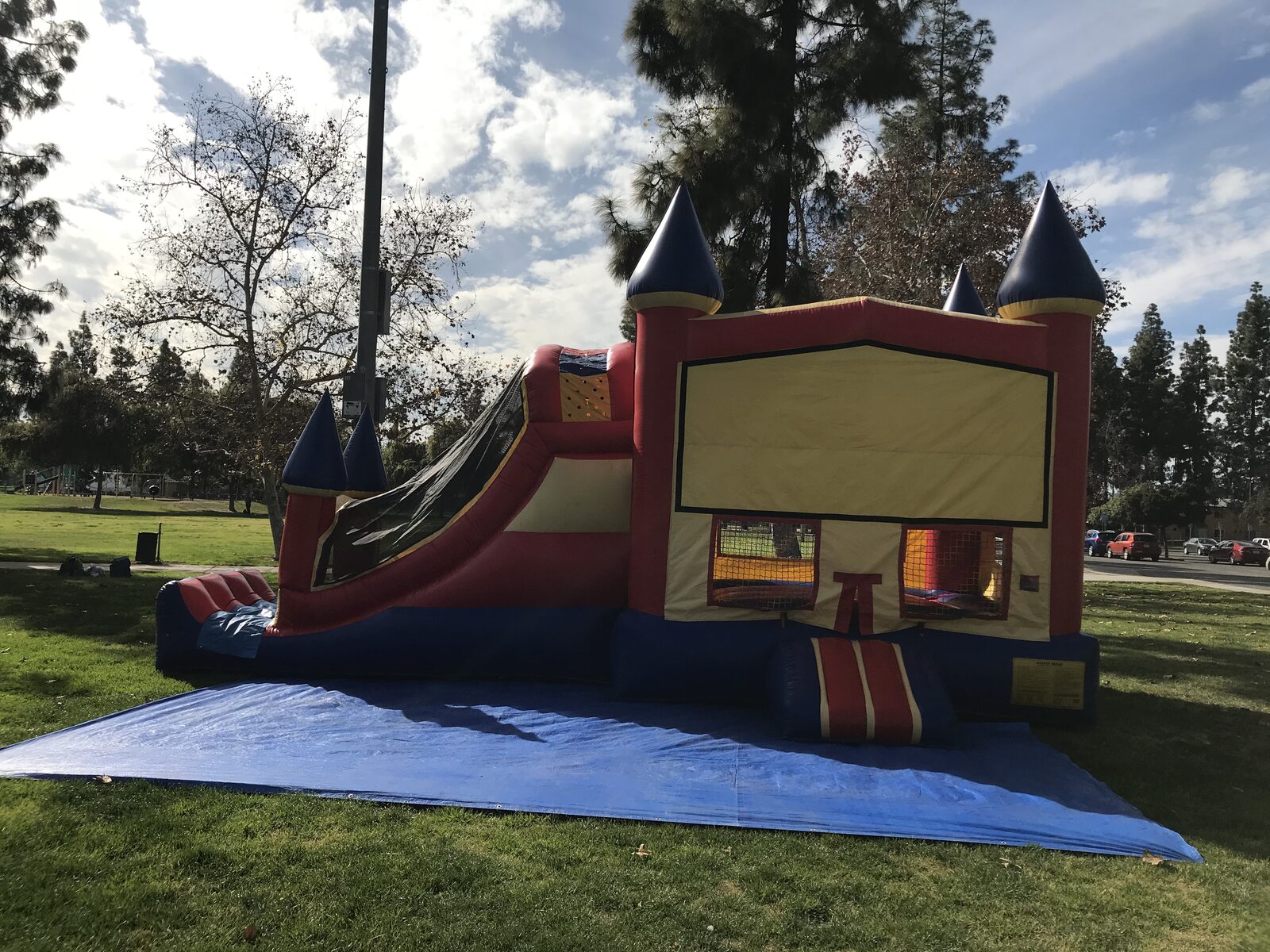 4n1 blue castle banner combo bounce house rental in San Diego, side view of the jump area and attached slide on a blue tarp
